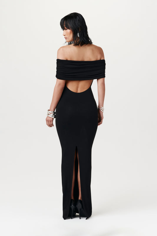 rear view of woman wearing a black off the shoulder max dress with back slit