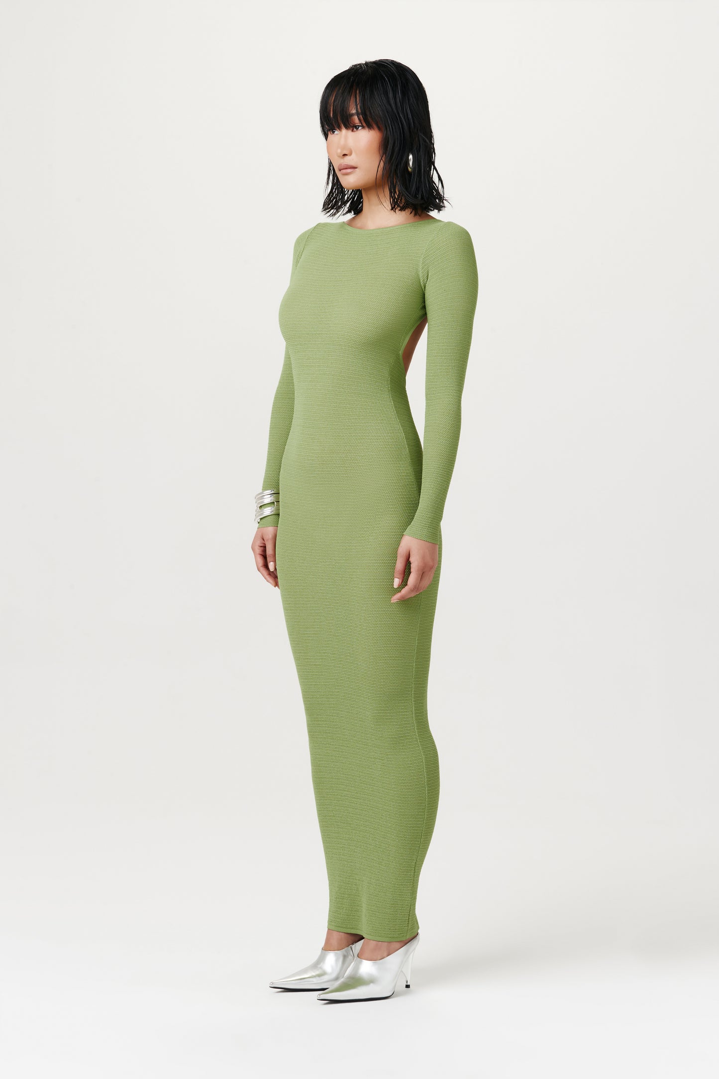 side view of woman wearing lime green long-sleeve maxi dress with silver heels