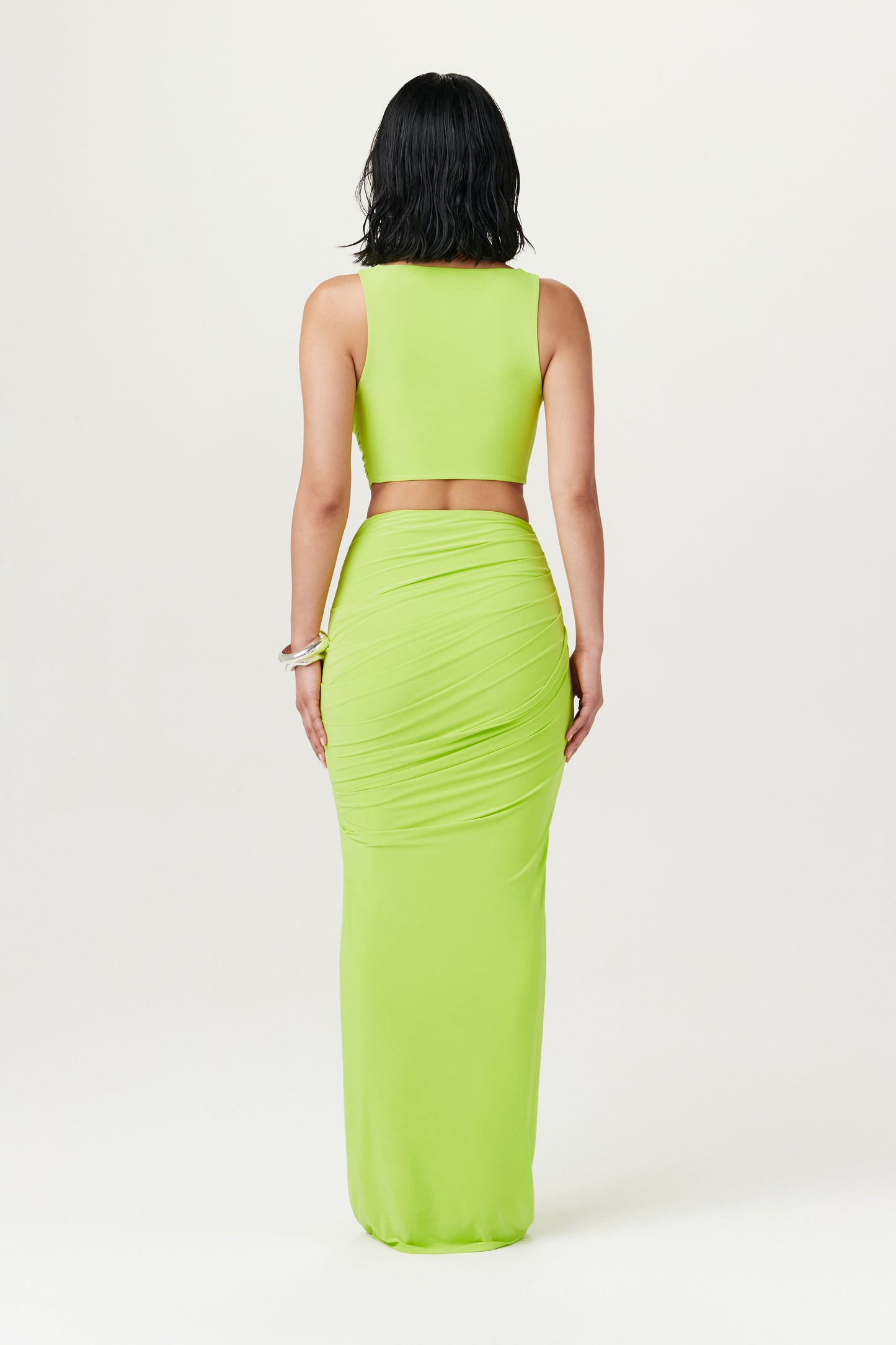 view of woman wearing lime green maxi skirt and top combo from behind